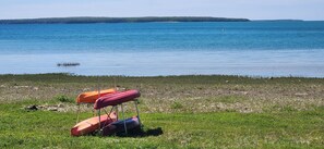 A grassy lakeside with a row of colorful kayaks. - "Sunrise Beach" Travel Trailer on 435' of Lake Michigan frontage- Fish on! (Garden)