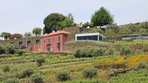 Una propietat a la vella amb un edifici vermell, una construcció blanca i un mur de pedra.