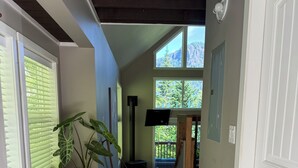 A hallway with wooden flooring, a bench, a rug, and a view of a balcony with greenery. - Peaceful, private 1-bedroom + loft bedroom home nestled in the forest. (Saltspring Island)