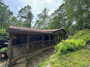Eine rustikale Holzhütte mit geneigtem Dach, umgeben von dichtem Wald.
