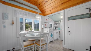A cozy kitchen with white cabinets, a wooden ceiling, and a sign reading "A Day With Friends And Family".