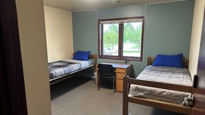A dormitory room with two single beds, a desk, and a chair. - Apartment Centrally Located (Plymouth)