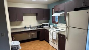 A compact kitchen with dark cabinets, a white refrigerator, a stove, a microwave, and a sink. - Apartment Centrally Located (Plymouth)