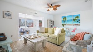 Ein Wohnzimmer mit einem grünen Sofa, einem Holztisch und einem Deckenventilator.
