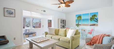A living room with a green sofa, a wooden coffee table, and a ceiling fan.