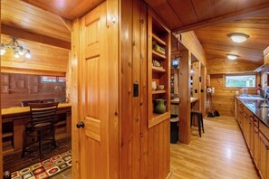 A wooden interior with a bar area, a dining table, and a kitchen with wooden cabinets and a sink.
