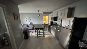 Een moderne keuken met roestvrijstalen apparatuur, een zithoek met een bank, en een klok aan de muur.