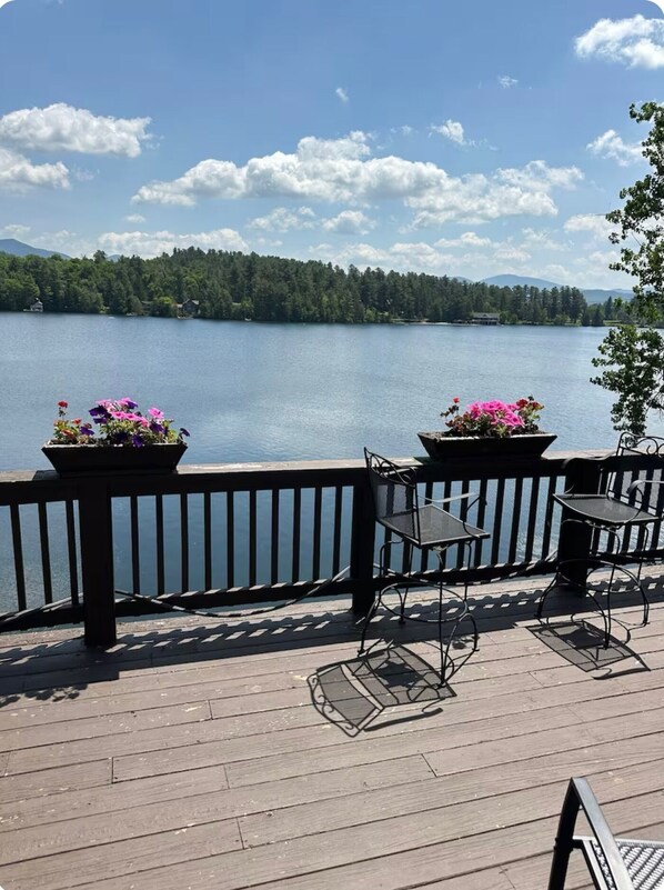 A wooden deck with outdoor seating and flower planters overlooking a lake.