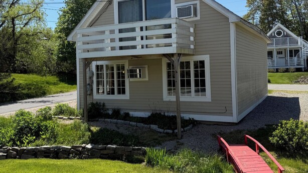 A single-story house with a front porch, a small deck, and a red wooden bridge leading to the entrance. - Shore Access from Charming 1 Bdrm Apt in Southwest Harbor, Acadia National Park (Southwest Harbor)