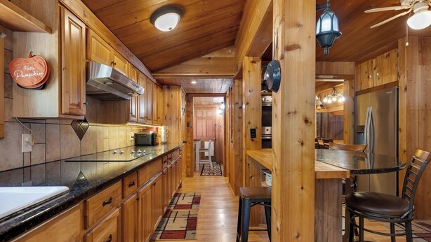 Una cocina tipo cabaña de madera con una isla central, un refrigerador y un comedor con sillas.