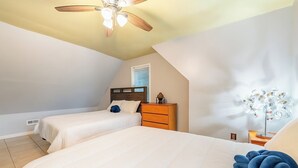 A bedroom with two beds, a ceiling fan, a dresser, and a decorative lamp. - Spacious 4BR Getaway w/ Games, Pier & Firepit (King and Queen Court House)
