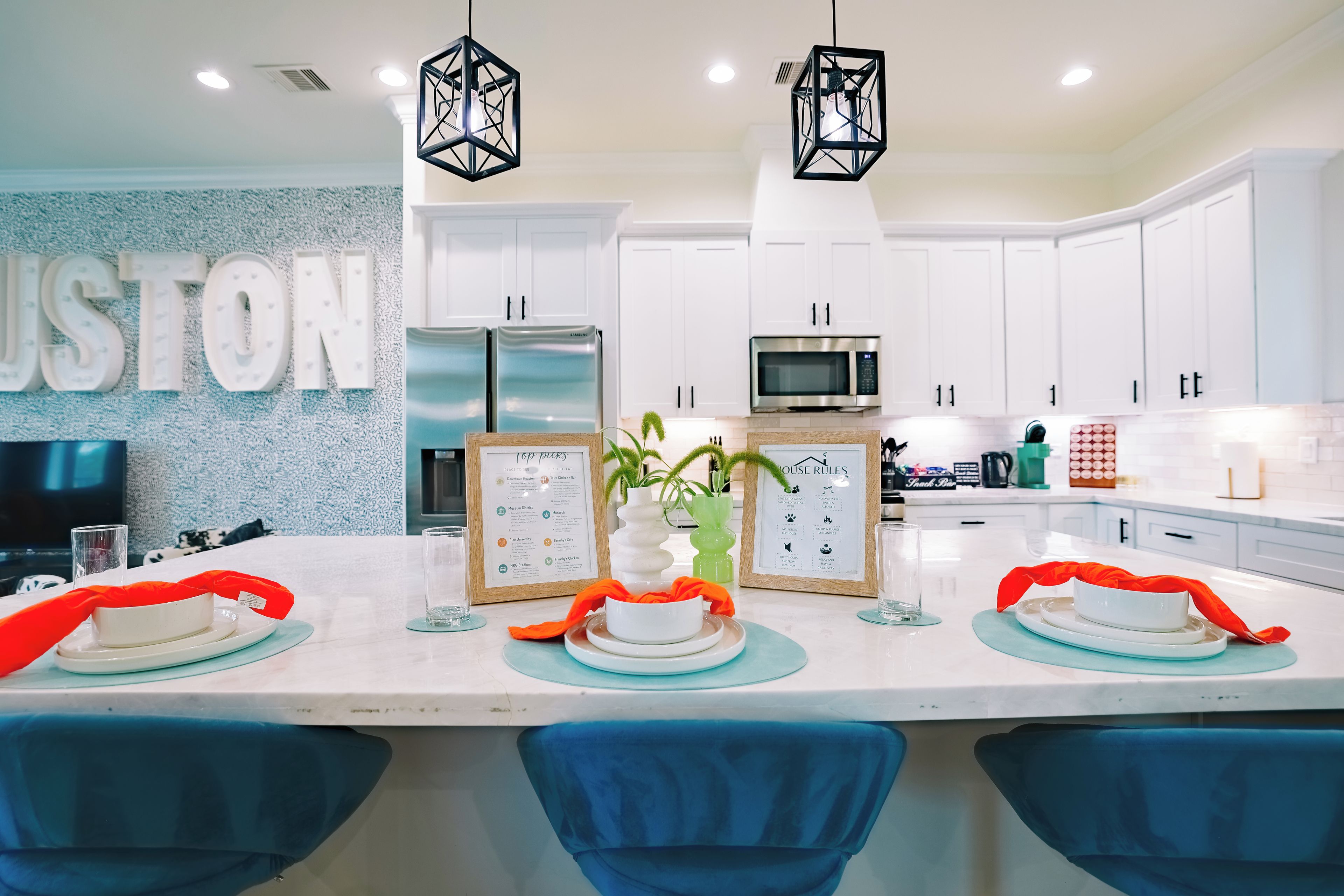 A modern kitchen with white cabinets, stainless steel appliances, and a central island with blue chairs.