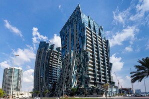 Un edificio moderno de gran altura con un diseño angular distintivo, con varios balcones y fachada de vidrio.