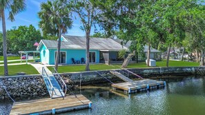 A waterfront property with a dock, a covered patio, and a building with a blue exterior. - New VRBO 2026 open dates-New 4/3 with heated pool, dock, kayaks, outdoor space (Crystal River)