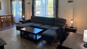 A modern living room with a sectional sofa, a dining table with chairs, and a small side table.