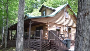 A wooden cabin with a porch, a covered deck, and a staircase leading to the entrance. - 3-bedroom cabin at Norris Lake, Sleeps 8 WiFi Lake access Covered boatslip (Speedwell)