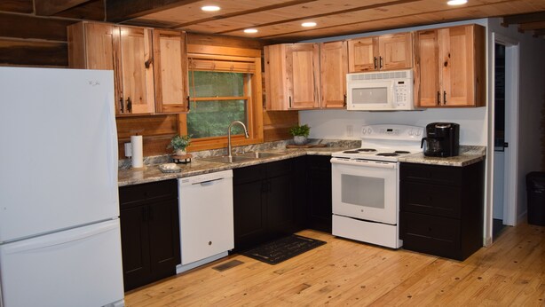A kitchen with wooden cabinets, a white refrigerator, a microwave, a stove, and a dishwasher. - 3-bedroom cabin at Norris Lake, Sleeps 8 WiFi Lake access Covered boatslip (Speedwell)