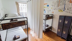 A dormitory room with bunk beds, a window with curtains, a wall map, and lockers. - Bunk Bed Room (4 Single Beds) (New York)