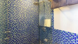 A bathroom with blue mosaic tiles, a glass shower enclosure, and a towel rack. - Bunk Bed Room (4 Single Beds) (New York)