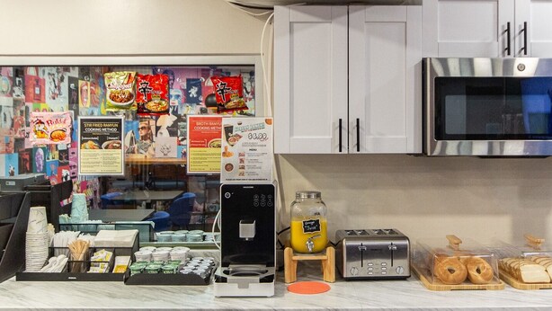 A kitchen area with a microwave, toaster, and various food items on the counter. - Bunk Bed Room (4 Single Beds) (New York)