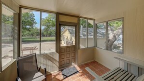 A sunroom with large windows, a bench, and a door leading outside. - RENOVATED-Vacation Cabin, Riverfront - Hunt, TX (Ingram)