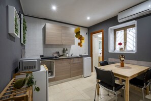 A modern kitchen with wooden cabinets, a built-in oven, and a dining area with a table and chairs. - Casa Ravanas - City Center Studio (Bari)