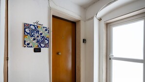 Un pasillo con una puerta de madera, una obra de arte en la pared que dice "Hogar" y un ventanal grande.