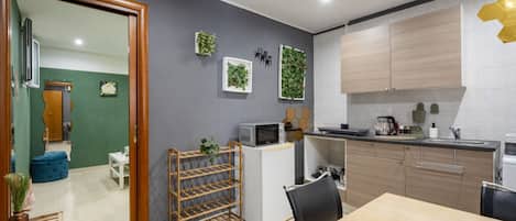 A compact kitchen with a microwave, sink, and cabinets. There is a small dining area with a table and chairs.