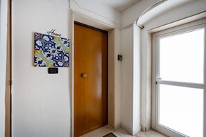 A hallway with a wooden door, a wall-mounted artwork labeled "Home," and a large window. - Casa Ravanas - City Center Studio (Bari)