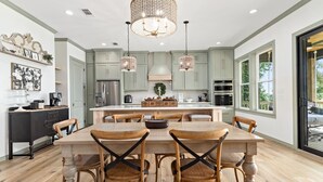 A modern kitchen with a central island, wooden chairs, and pendant lighting. - The Magnolia Ridge Retreat (Jasper)