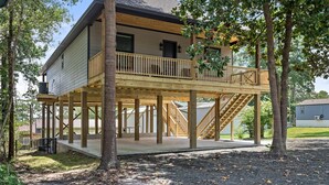 A two-story house with a wooden deck and a staircase leading to a balcony. - The Magnolia Ridge Retreat (Jasper)