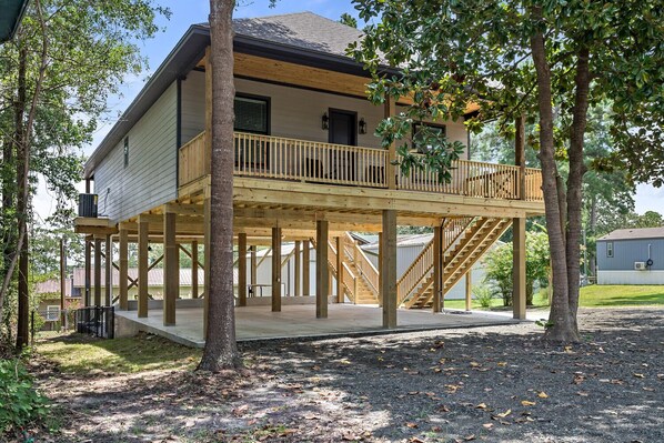 A two-story house with a wooden deck and a staircase leading to a balcony.