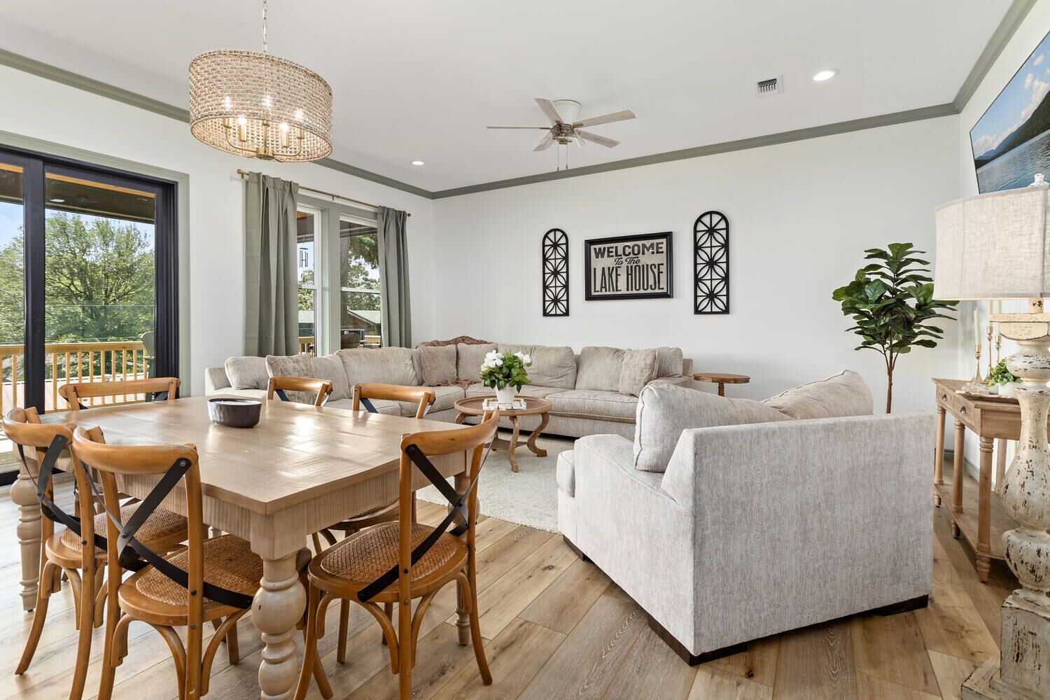 A spacious living area with a wooden dining table, grey sofas, and a ceiling fan.