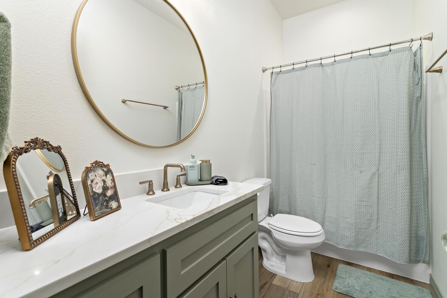 A bathroom with a white sink, two mirrors, a toilet, and a shower curtain.