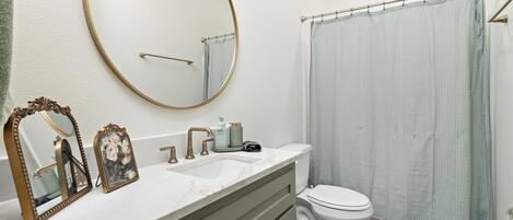 A bathroom with a white sink, two mirrors, a toilet, and a shower curtain.