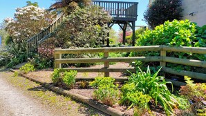 Een tuinpad dat leidt naar een houten terras met een trap.