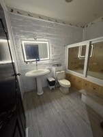 Un baño con lavamanos, inodoro y espejo blancos.