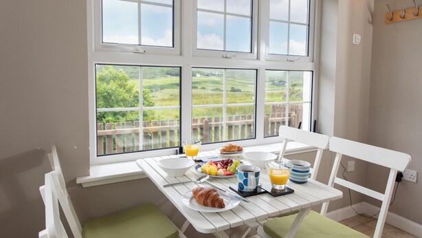 Ein Frühstückstisch mit Blick auf eine ländliche Landschaft durch große Fenster.
