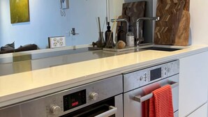 A modern kitchen with a Bosch oven, a digital clock, and a red towel hanging on the oven handle. - Indulgent stay in trendy Prahran (Prahran)