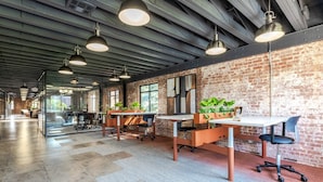 Un espace de bureau avec des murs en briques apparentes, des bureaux modernes et des luminaires suspendus.
