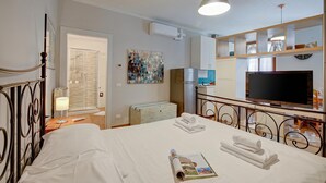 A hotel room with a bed, a television, a desk, a mirror, and a window. - Vicky Loft Gardone-relax & Vittoriale, Gardone Riviera, Italy (Gardone Riviera)