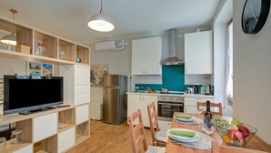 A compact kitchen with a TV, refrigerator, oven, and dining area with chairs and a table. - Vicky Loft Gardone-relax & Vittoriale, Gardone Riviera, Italy (Gardone Riviera)