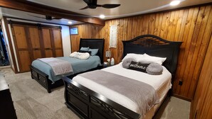 Une chambre avec deux lits, des murs en bois, un ventilateur de plafond et une petite table de chevet avec une lampe.