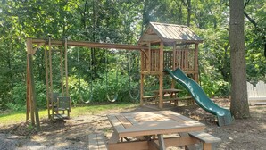 Une aire de jeux avec des balançoires, un toboggan et des tables de pique-nique.