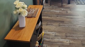 Une pièce avec un bureau en bois, un vase de fleurs blanches, une horloge et un panneau mural en bois.
