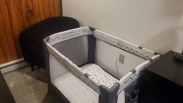 Un berceau pour bébé avec un matelas à motifs blancs et gris, un mur en bois, une citation inspirante encadrée et une chaise de bureau noire.