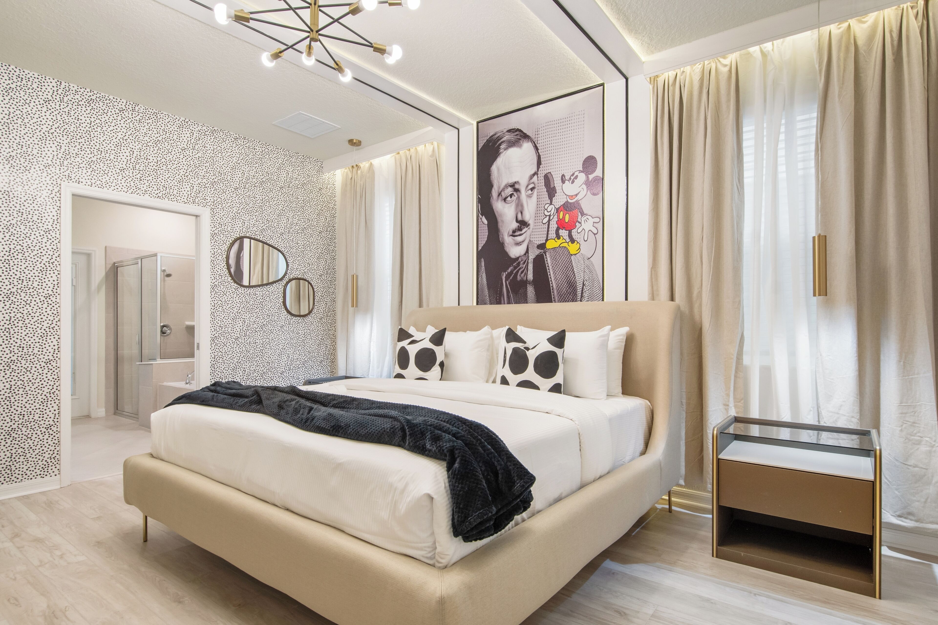 Un dormitorio moderno con una cama grande, una mesita de noche, un espejo y un póster en la pared.