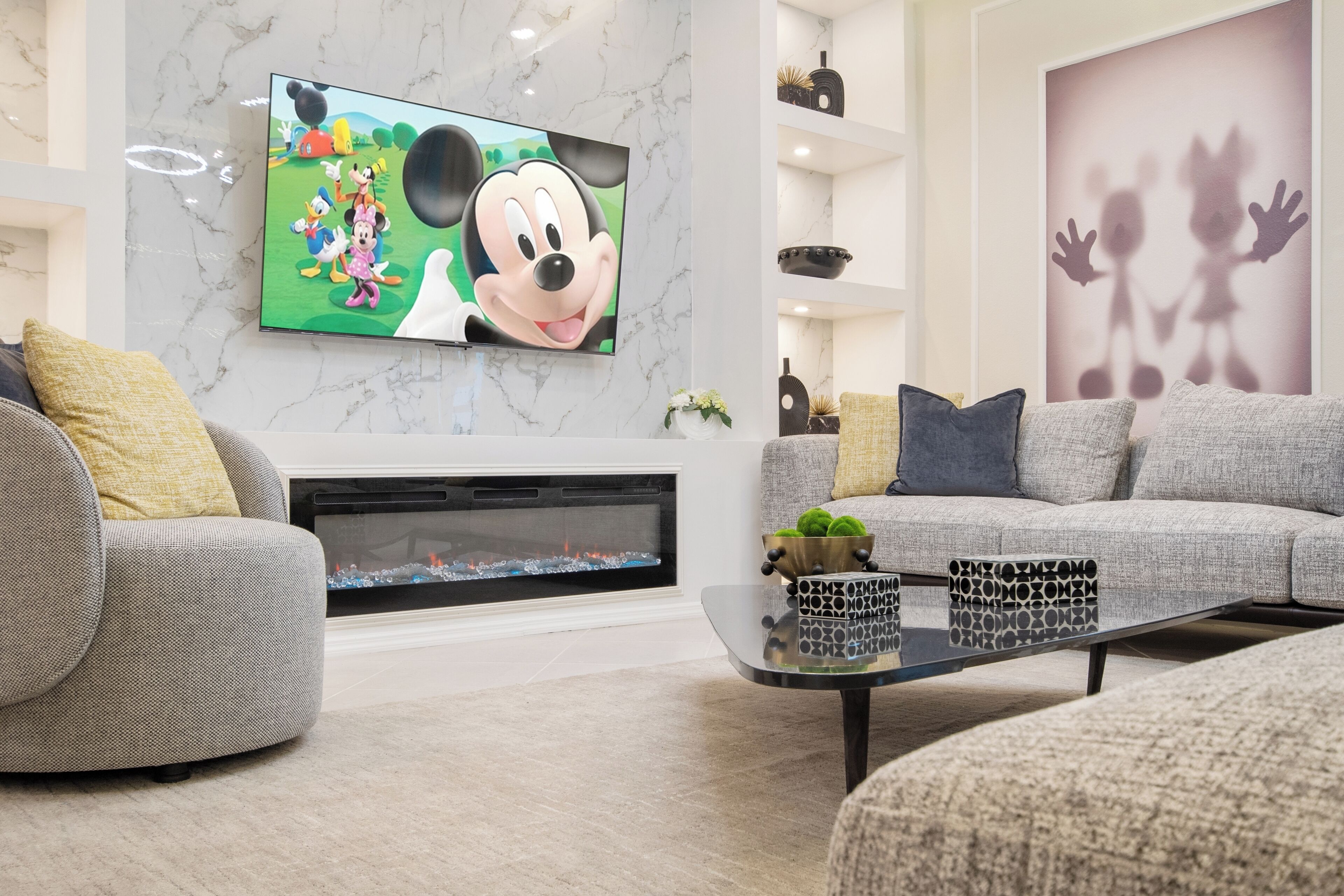 A modern living room with a large flat-screen TV, a fireplace, and a comfortable seating area.