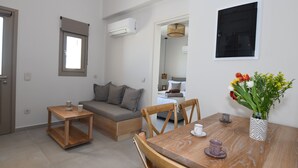 Un espacio habitable compacto con sofá, mesa de madera y zona de comedor.