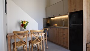 Una cocina moderna con armarios de madera, un refrigerador negro y un comedor con dos sillas de madera y un jarrón de flores.